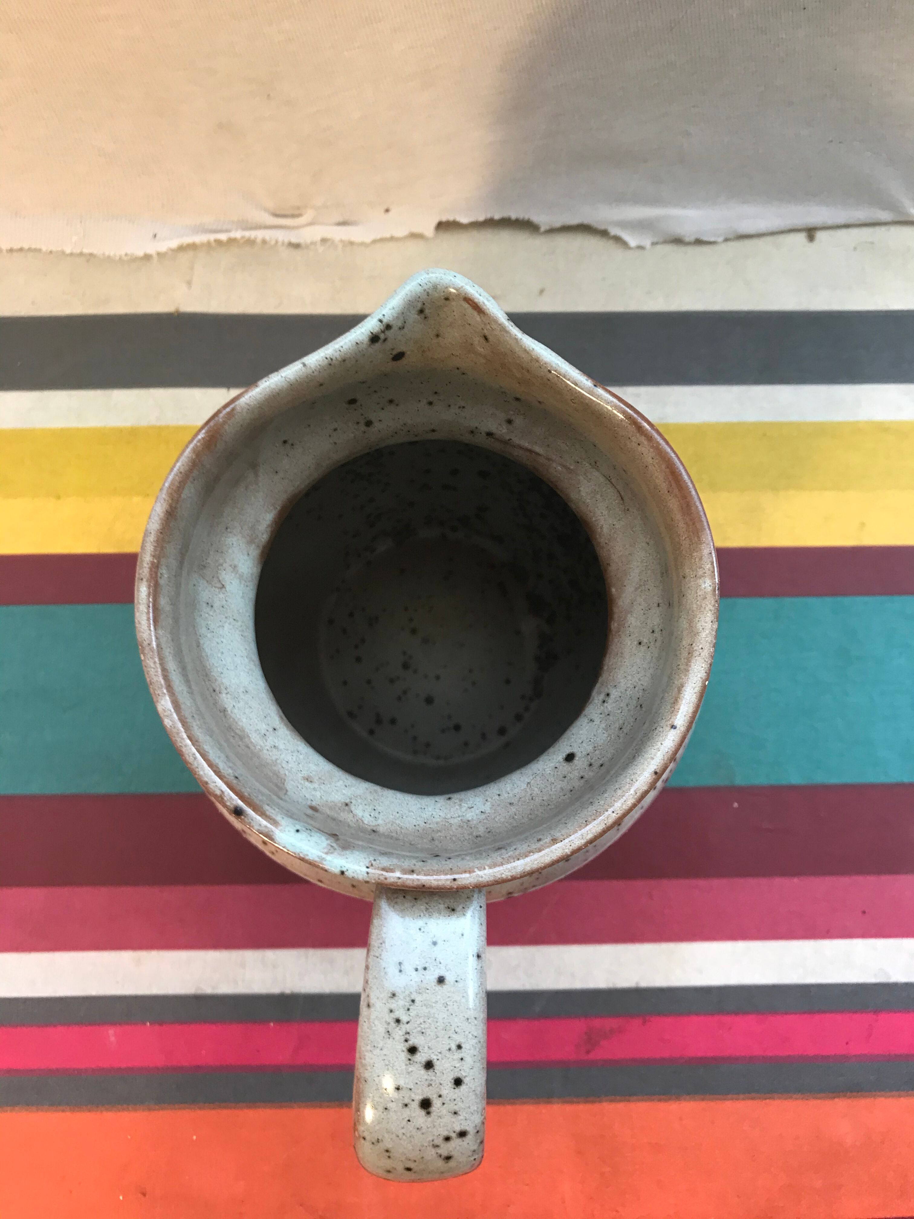 Old gray pitcher with black drawings and vintage stamped handle