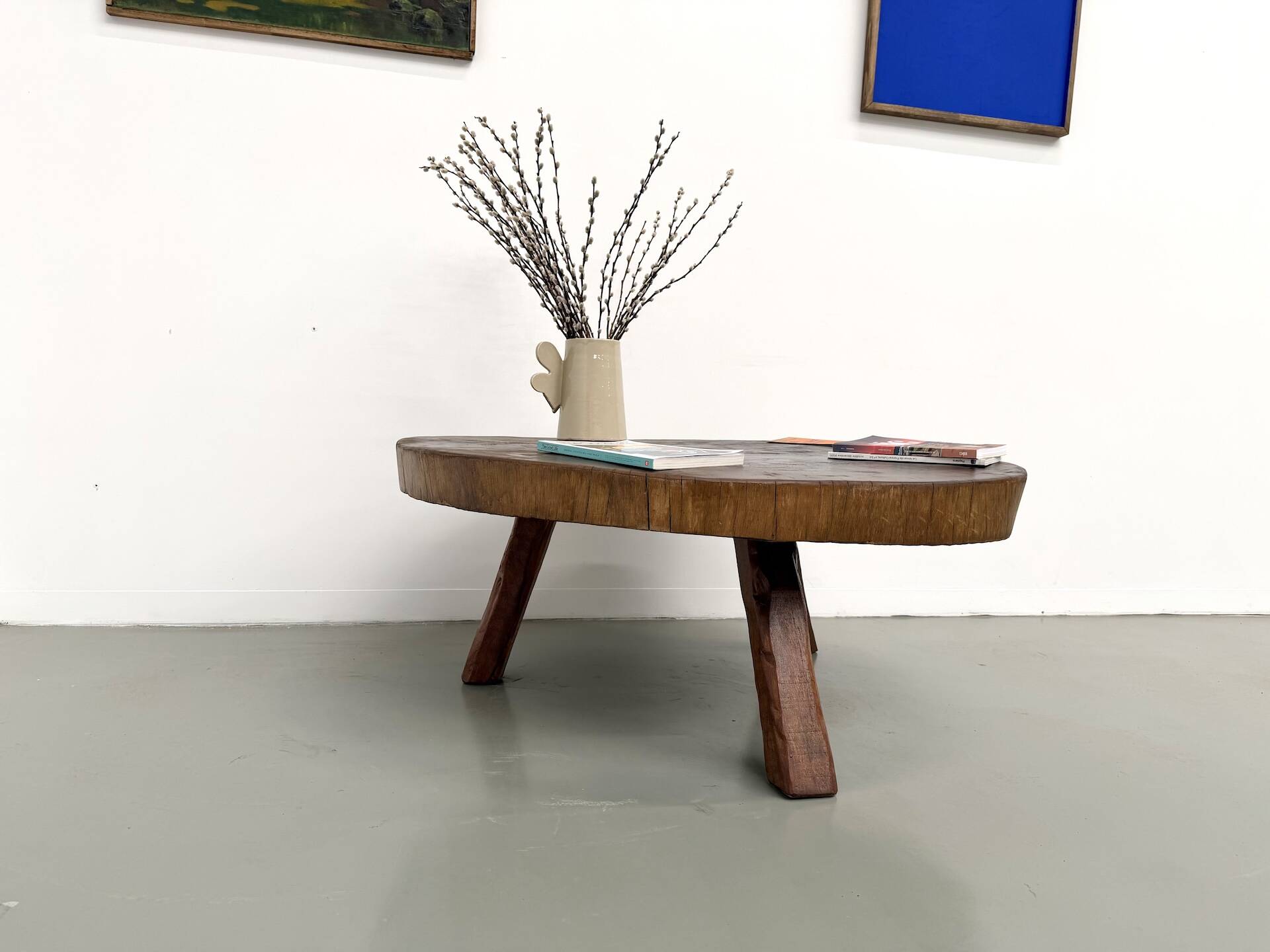 Brutalist coffee table in solid teak, monolithic slab, tripod base.