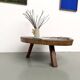 Brutalist coffee table in solid teak, monolithic slab, tripod base.