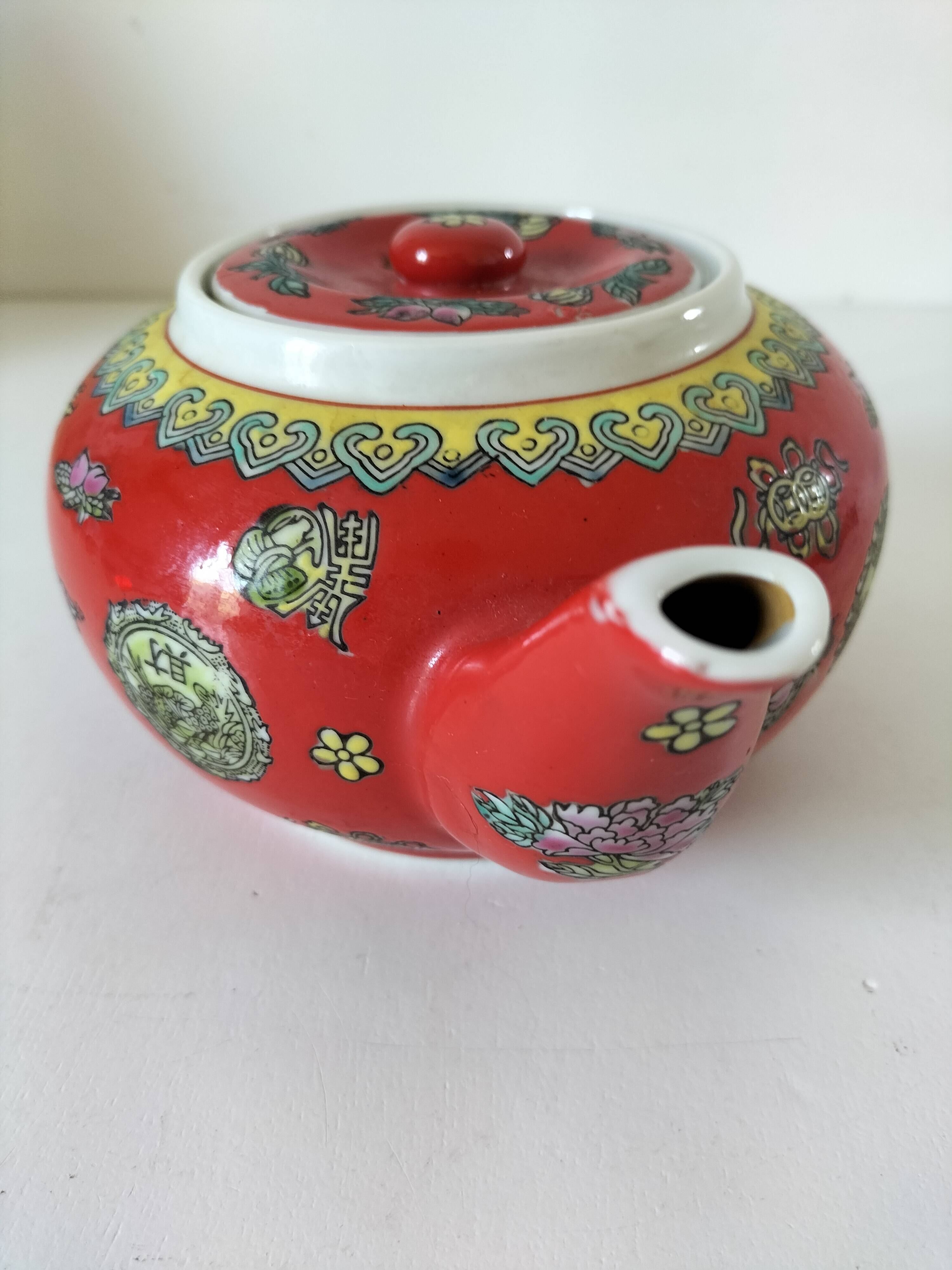 Vintage red Chinese teapot decorated with dragons and symbols.