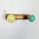 Vintage wall coat rack with 2 yellow and green balls.