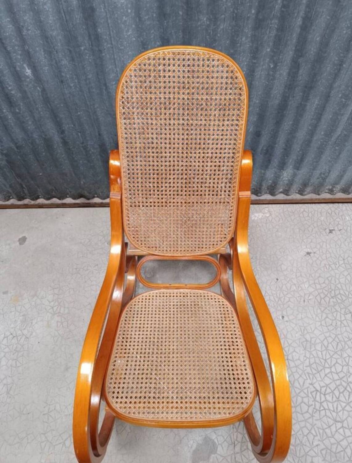 Curved wooden rocking chair with wicker cane rattan.