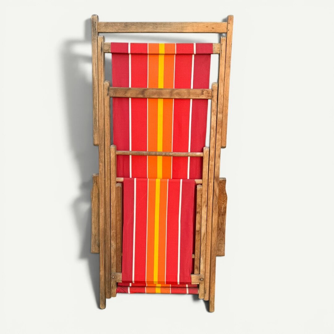 Vintage deck chair with red and orange striped fabric, original patina.