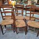 Set of six rustic chairs in natural wood with straw seats.