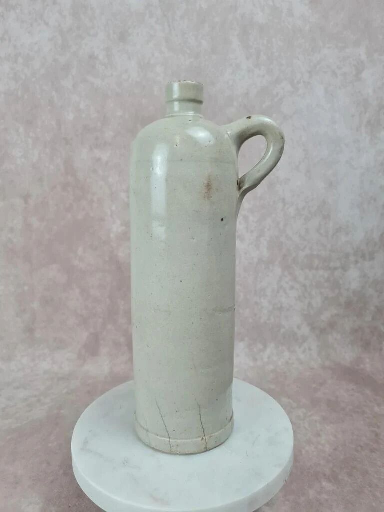 Antique beige glazed stoneware bottle from the 19th century, with a handle, vintage decor.