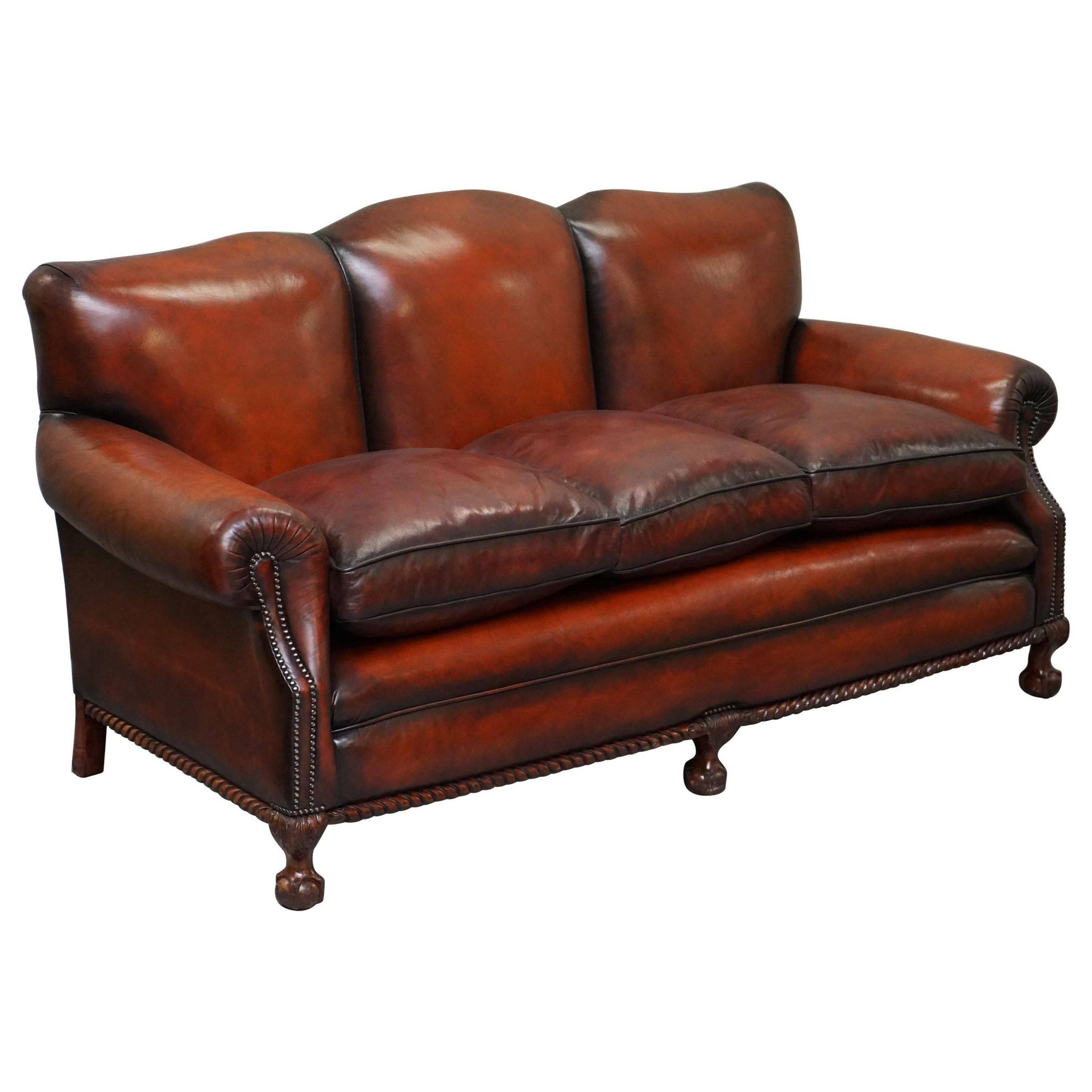 Restored Victorian sofa in leather with claw feet and feather cushions.