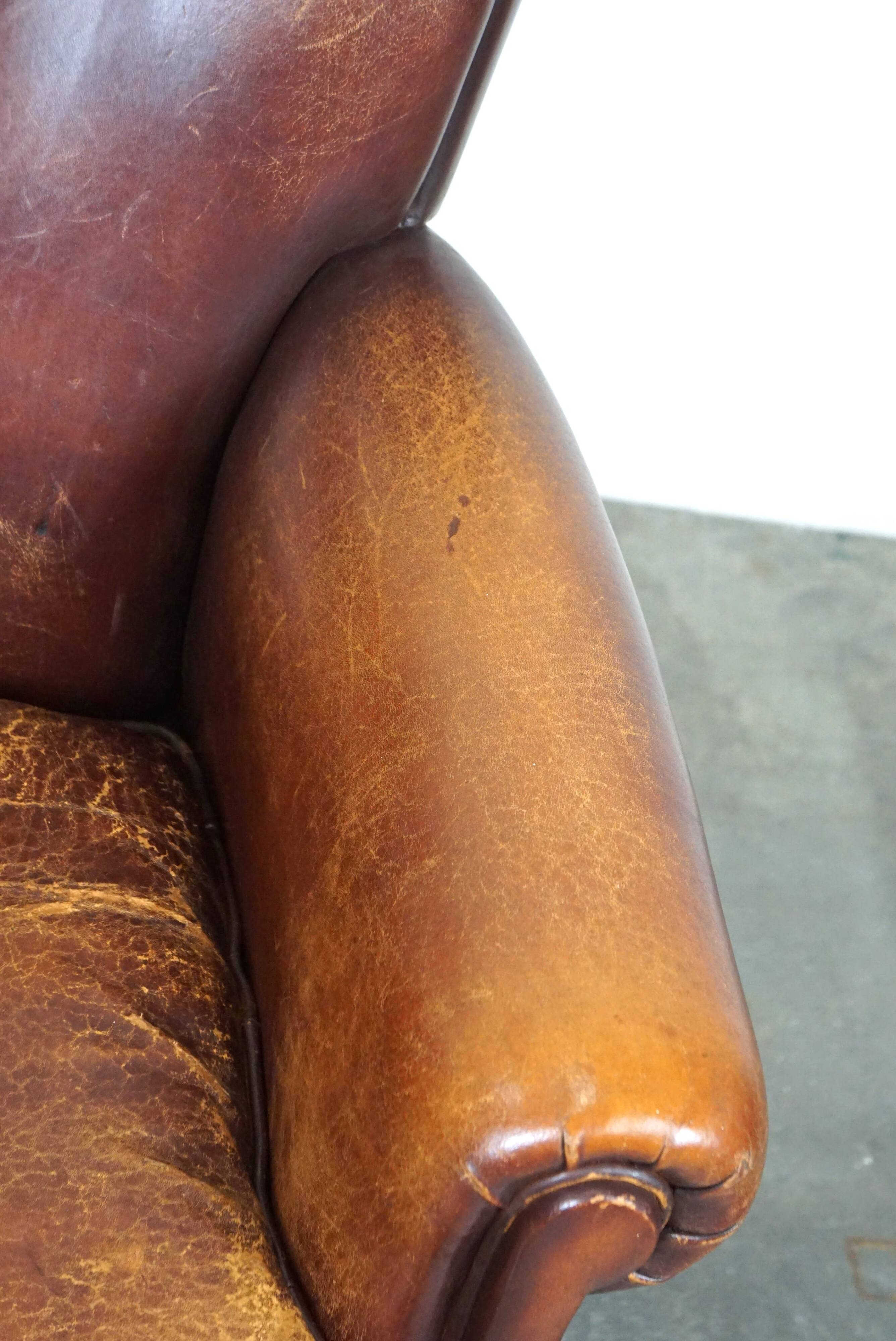 Fauteuil en cuir de mouton robuste et usé mais très confortable avec une belle patine