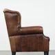 Sheepskin wingback armchair with decorative nails and black piping