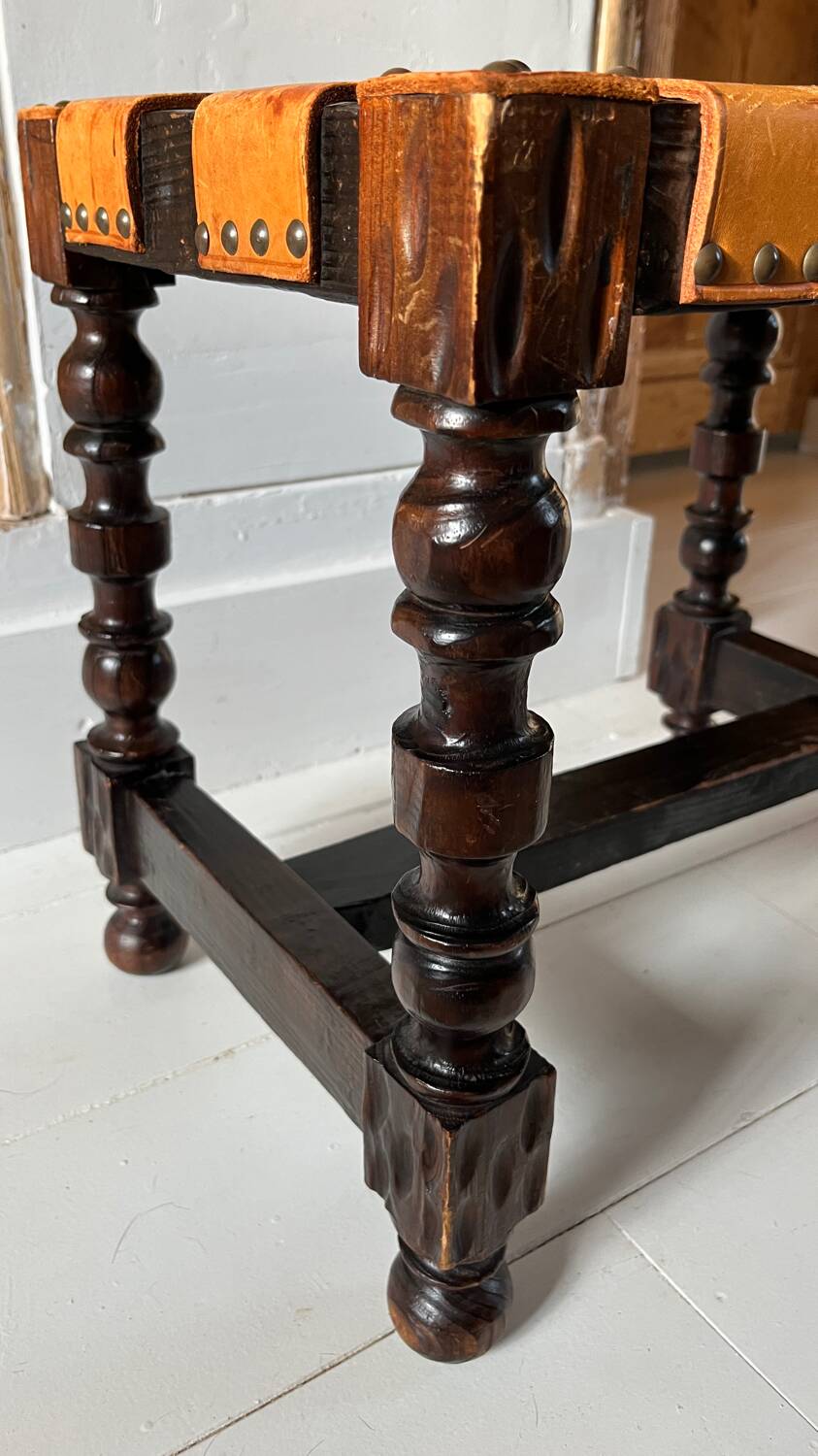 Antique turned wooden stool with woven leather.