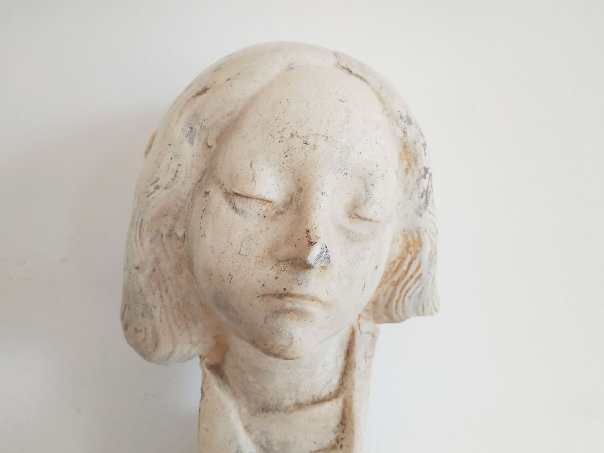 Bust of woman in plaster on pedestal with inscription