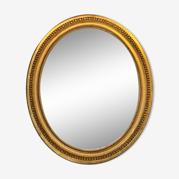 Oval mirror in carved wood, stuccoed and gilded with leaf Louis XVI style late nineteenth century