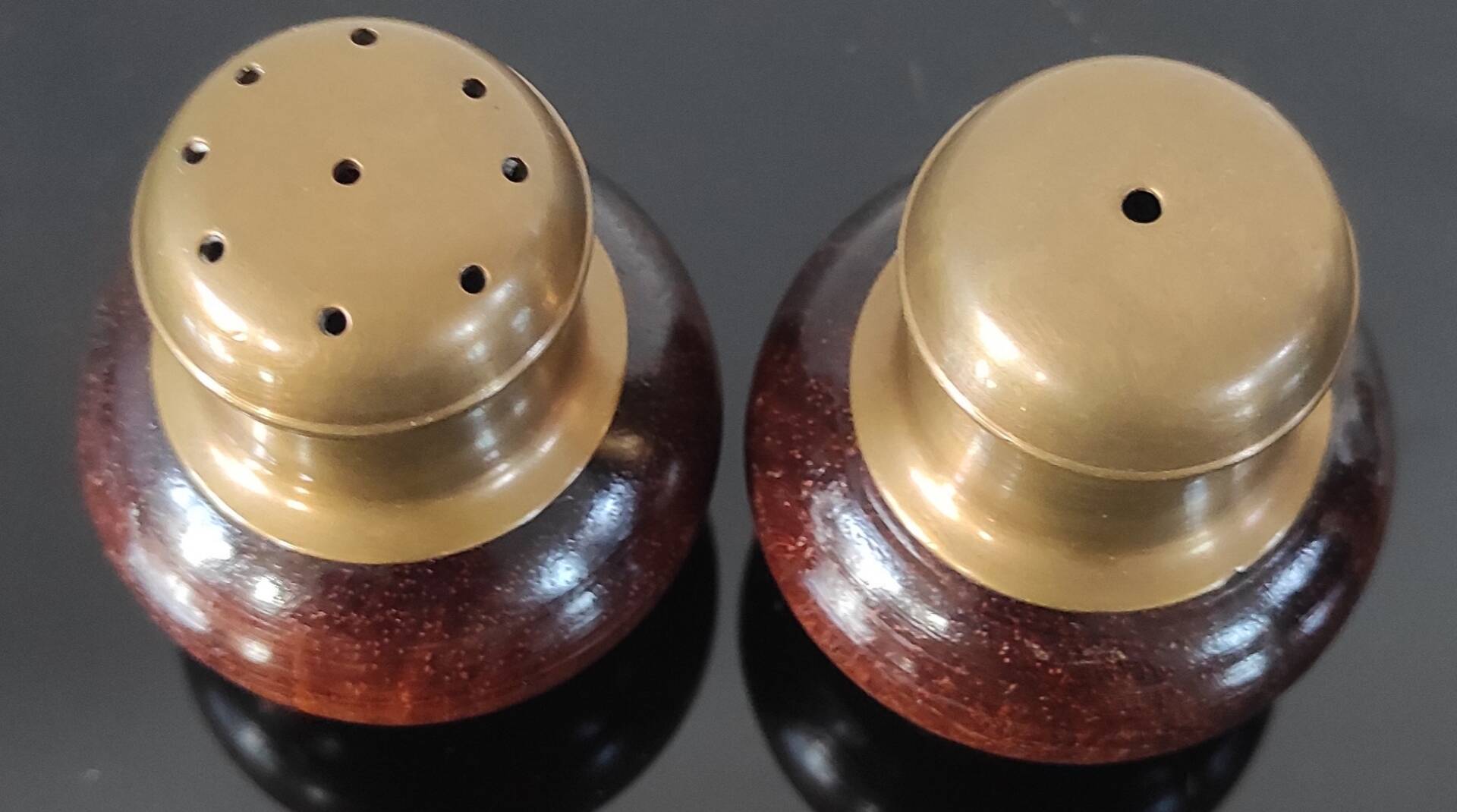 Vintage salt and pepper shaker duo in brass and turned wood.