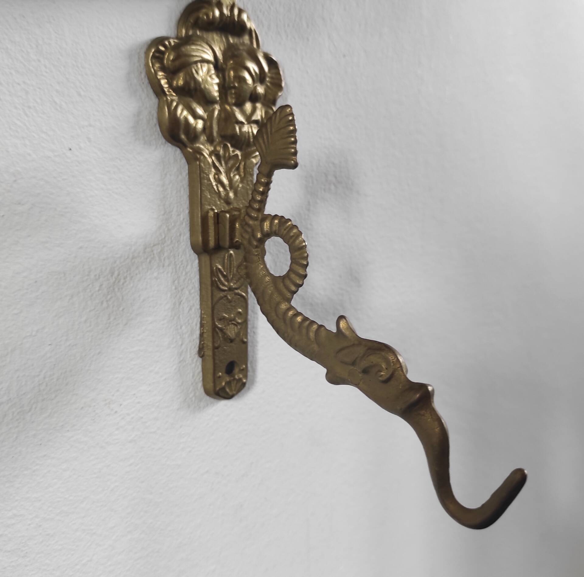 Vintage brass coat hook with marine creature motif and medallion.