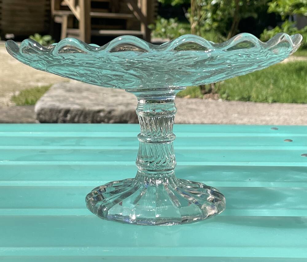 Footed bowl or pressed glass compote with floral decoration for table decor.
