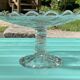 Footed bowl or pressed glass compote with floral decoration for table decor.