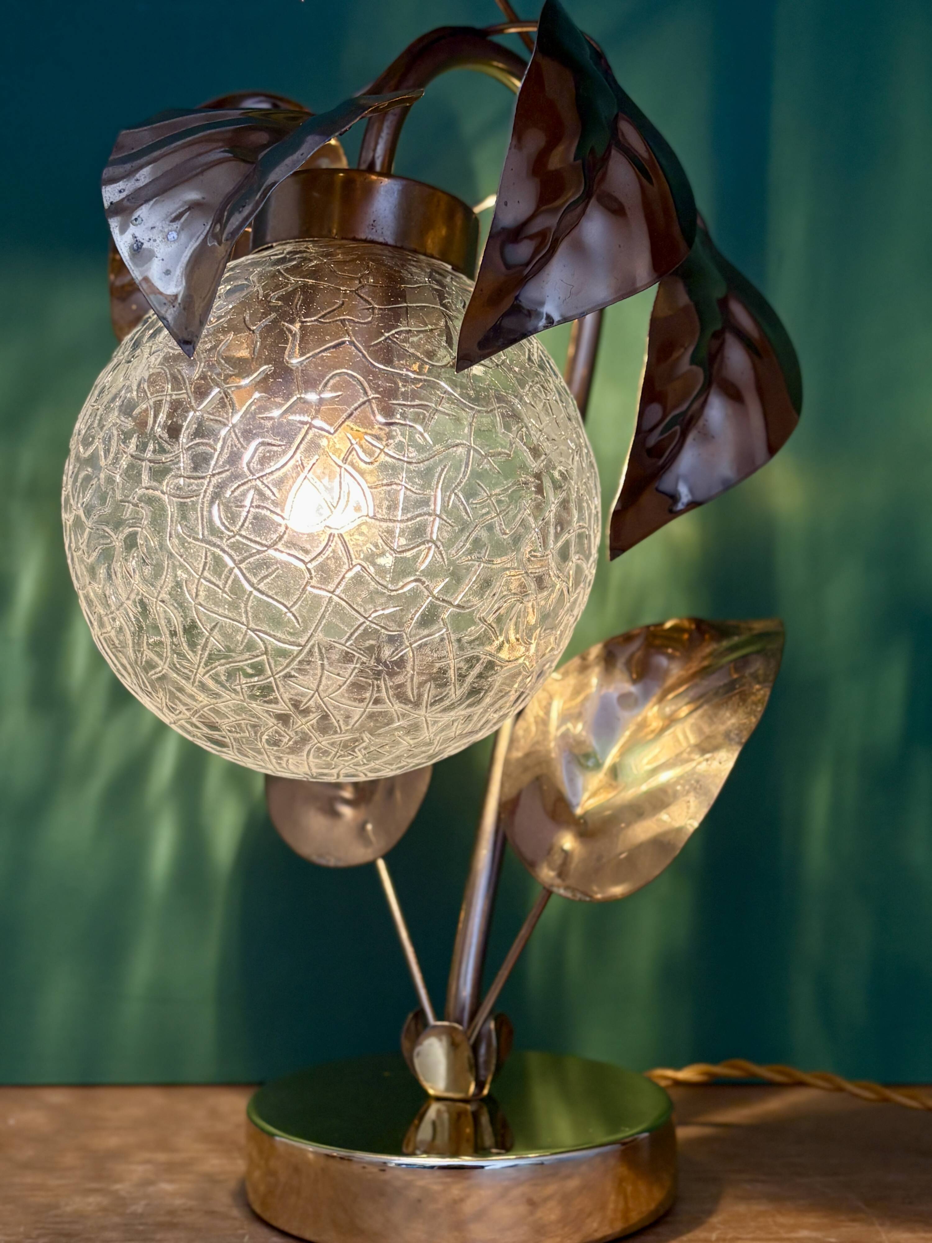 Vintage lamp with brass leaf design and transparent glass globe.