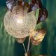 Vintage lamp with brass leaf design and transparent glass globe.