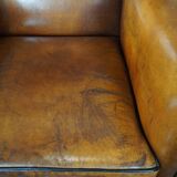 Art deco armchair in sheepskin with black piping and decorative nails