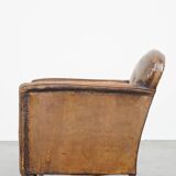 Fauteuil ancien en cuir de mouton sur roulettes et patiné