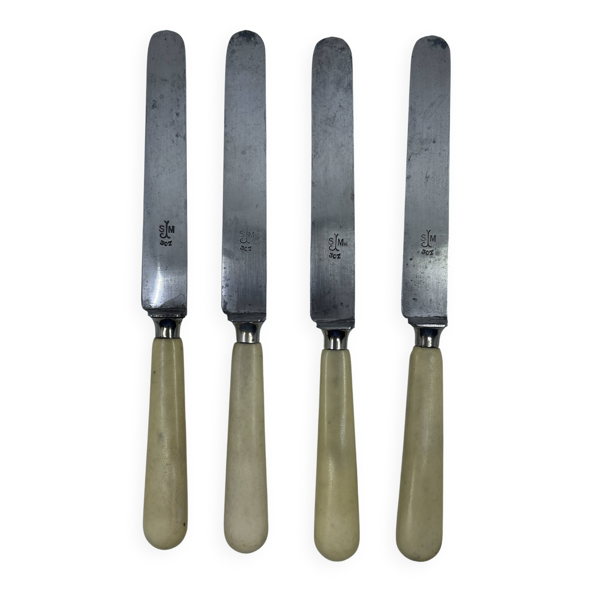 Set of 4 dessert knives with rounded blades and smooth ivory resin handles.