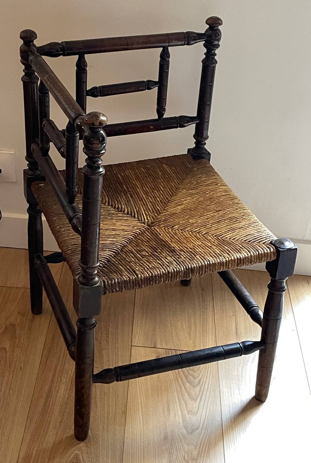 Corner chair made of turned wood with a straw seat.
