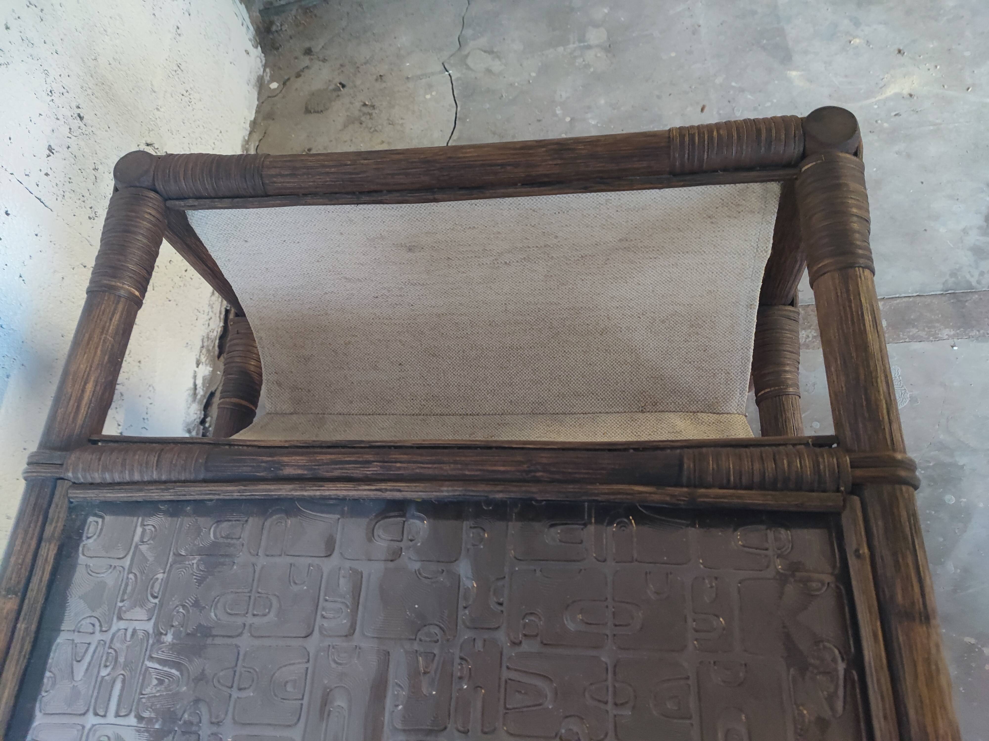 Relaxed armchair in bamboo and rattan with its small side table. Beige linen cushion.