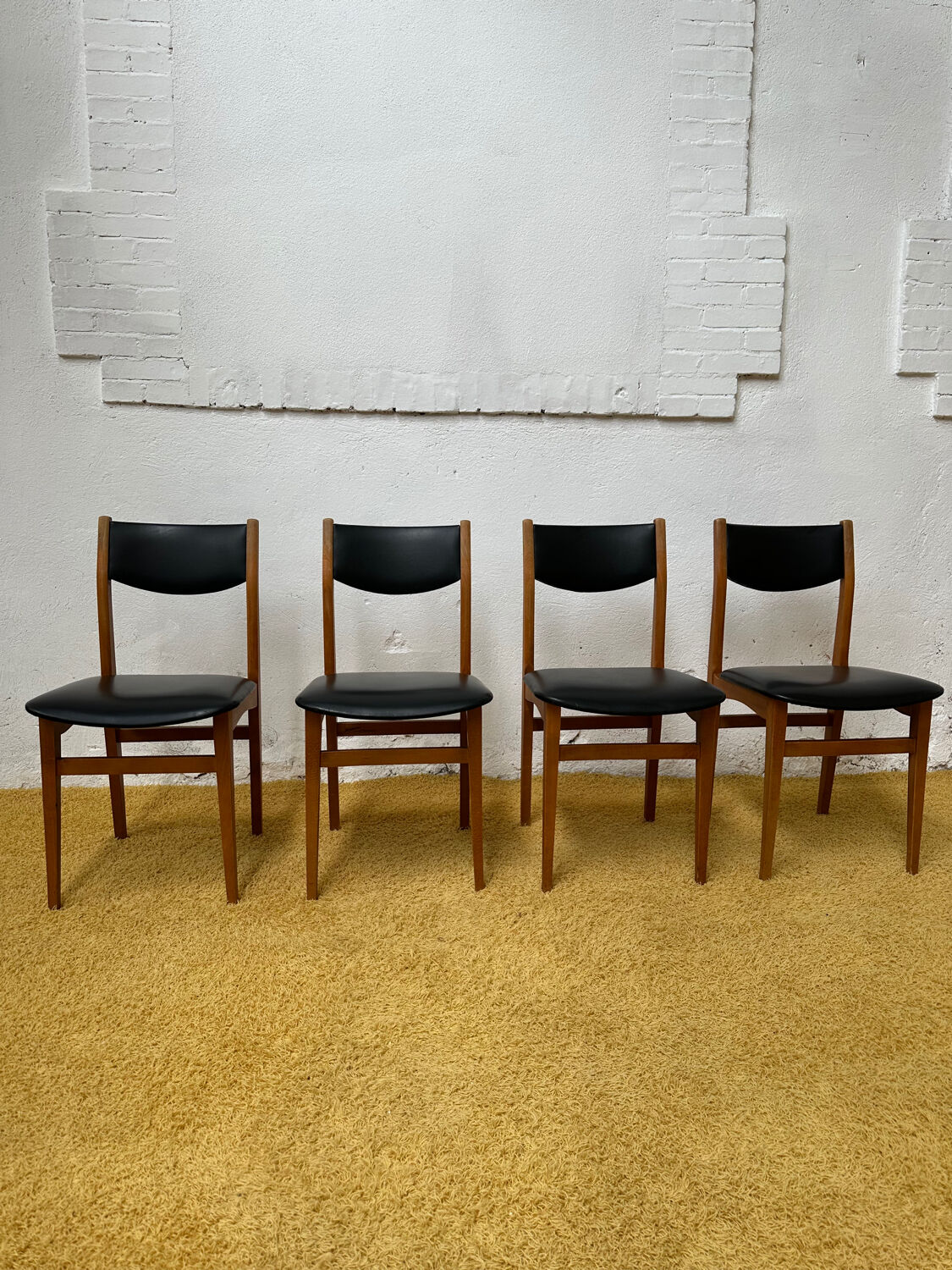 4 Scandinavian chairs in teak and black faux leather.