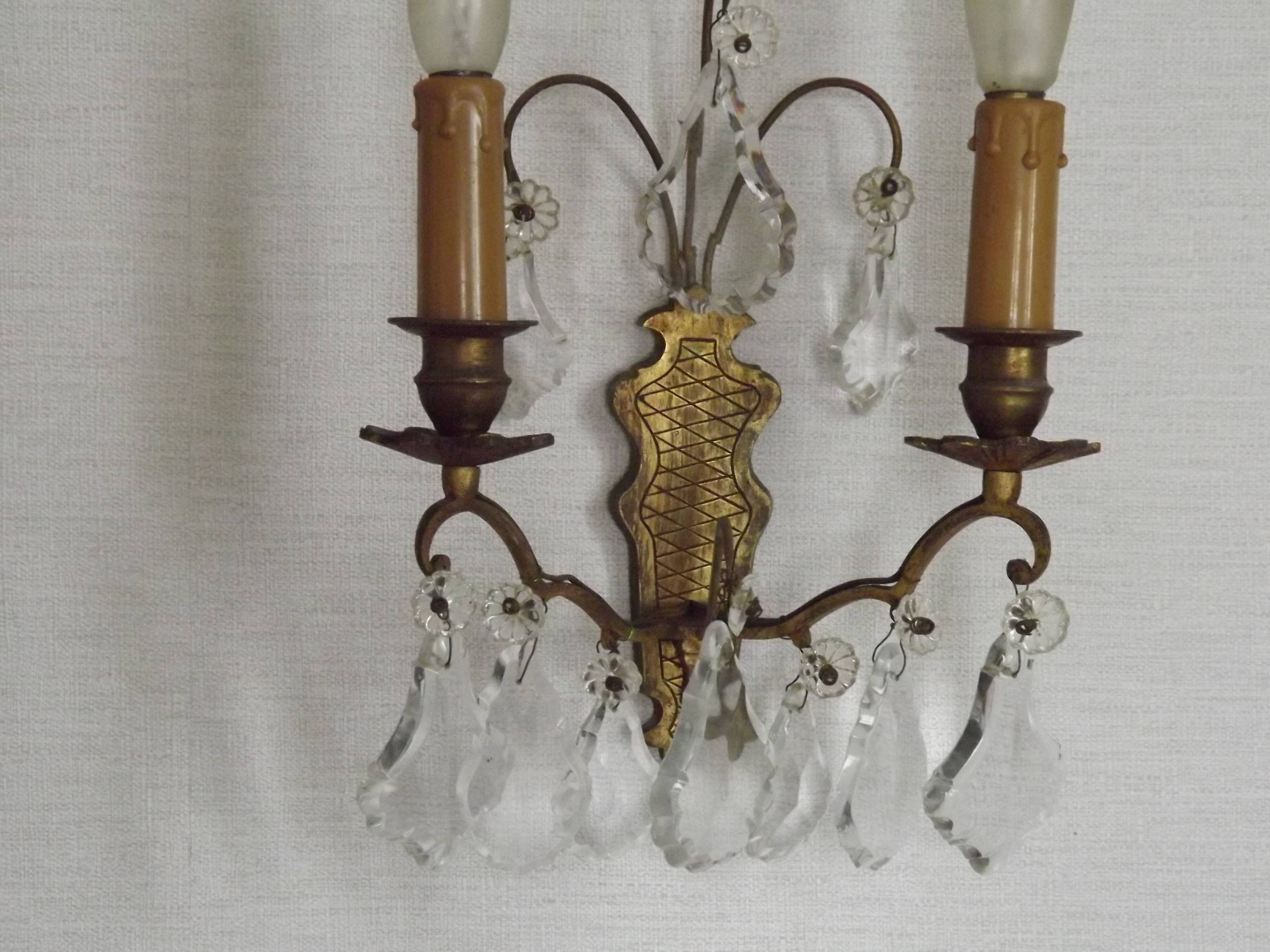 Pair of French antique brass double wall lights with assorted crystals.