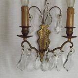 Pair of French antique brass double wall lights with assorted crystals.