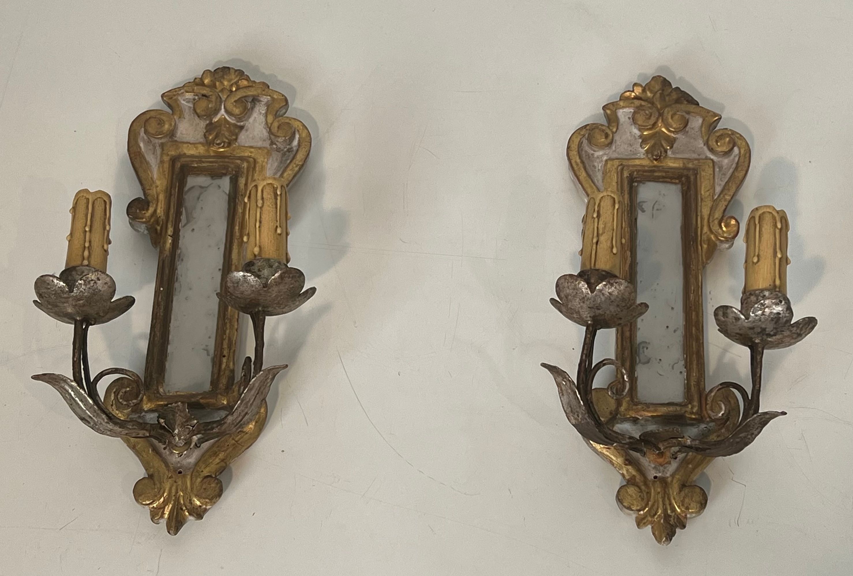 Pair of wall sconces in carved wood and silvered and gilded patinated metal with a central mirror.