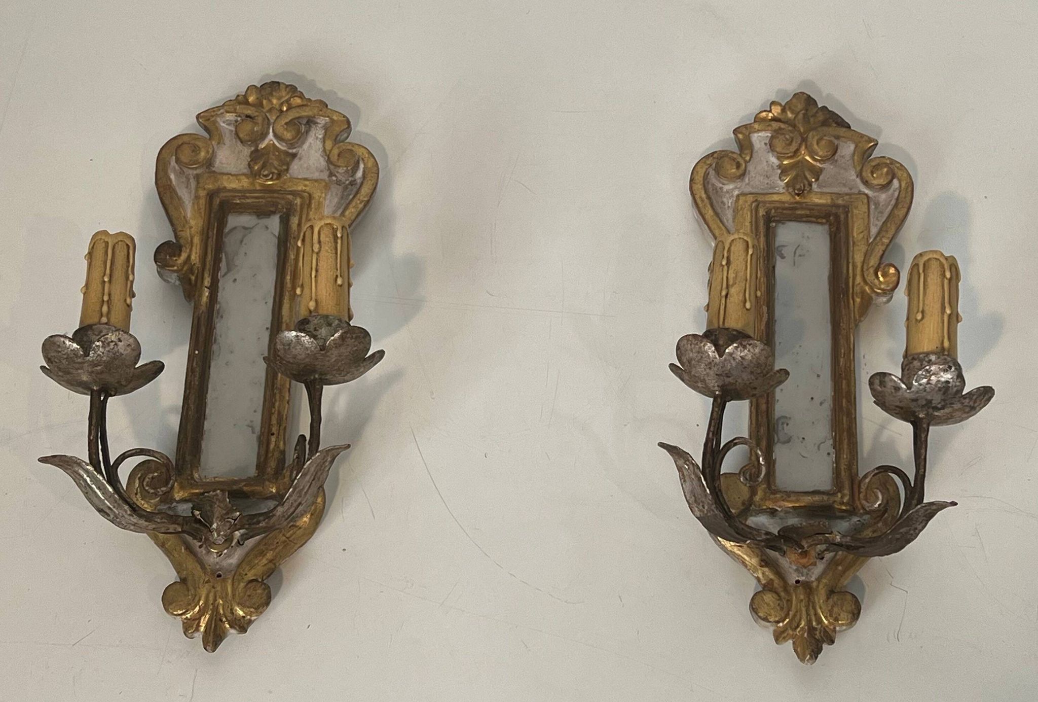 Pair of wall sconces in carved wood and silvered and gilded patinated metal with a central mirror.
