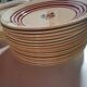 lot service vaisselles de gien beige avec rayures rouge bordeaux et dessin fleurs au centre, en faie