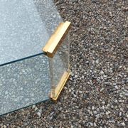 1970s designer coffee table in glass, plexiglass, and gold metal.