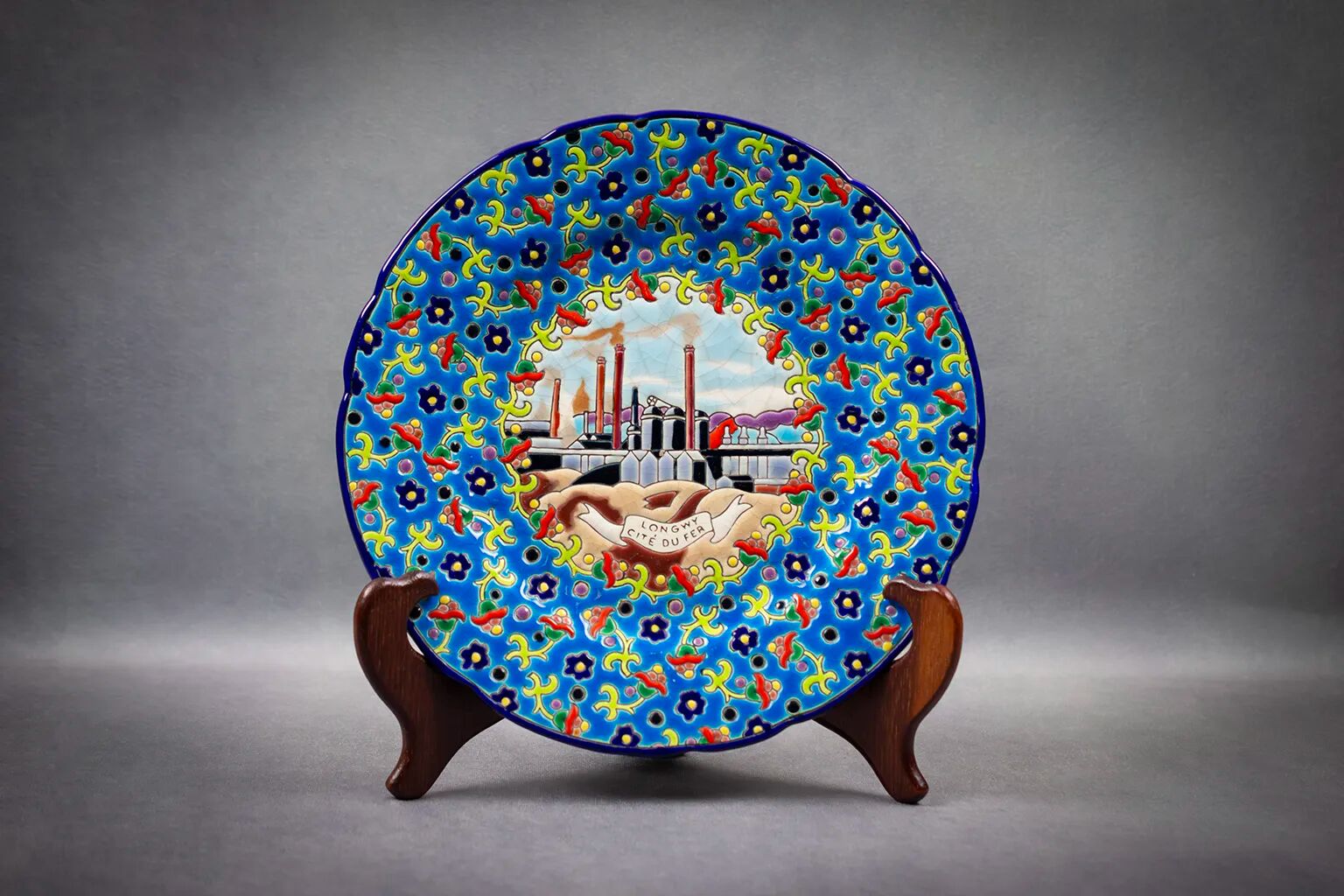 Longwy plate with polychrome enamels, decorated with the "City of Iron" motif.