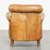 Comfortable, cozy armchair made of sheepskin leather with a neat finish and decorative nailhead trim
