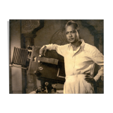 Photographie d'un réalisateur indien accoudé à sa caméra