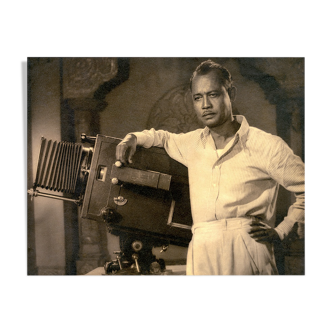 Photographie d'un réalisateur indien accoudé à sa caméra