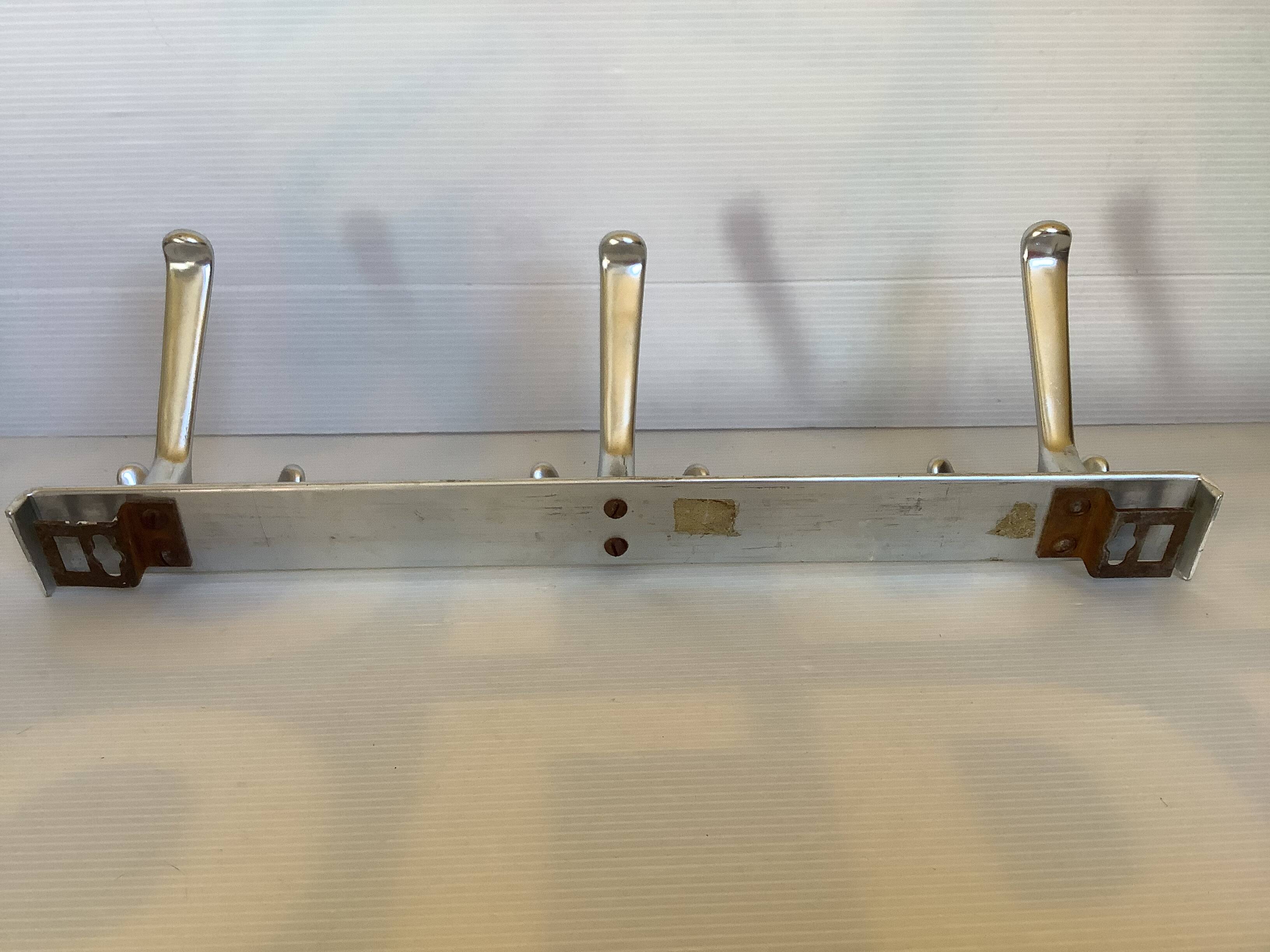 Stainless steel coat rack with three double hooks.