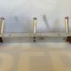 Stainless steel coat rack with three double hooks.