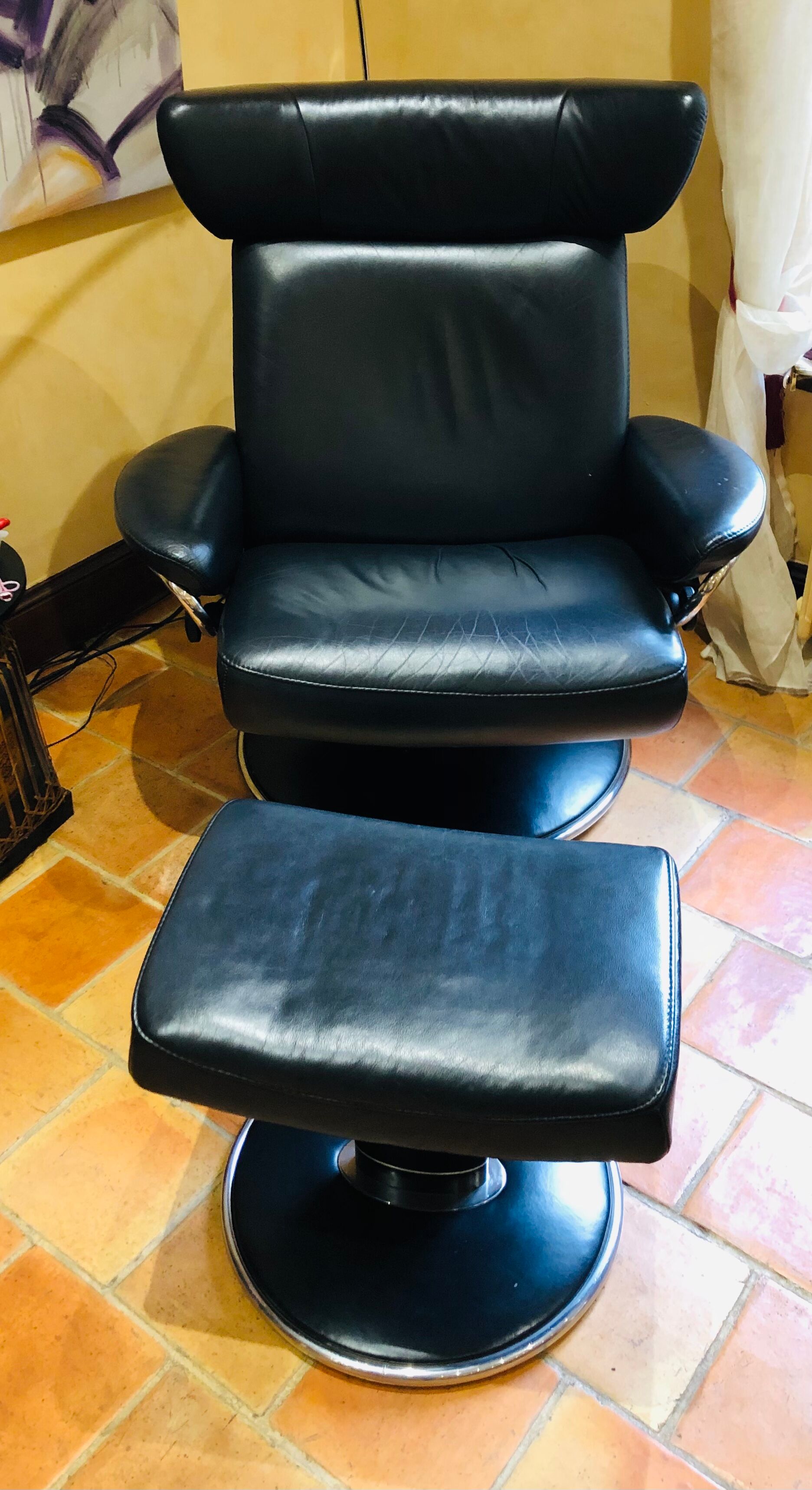 Black leather armchair stressless model jazz and its footrest