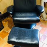 Black leather armchair stressless model jazz and its footrest