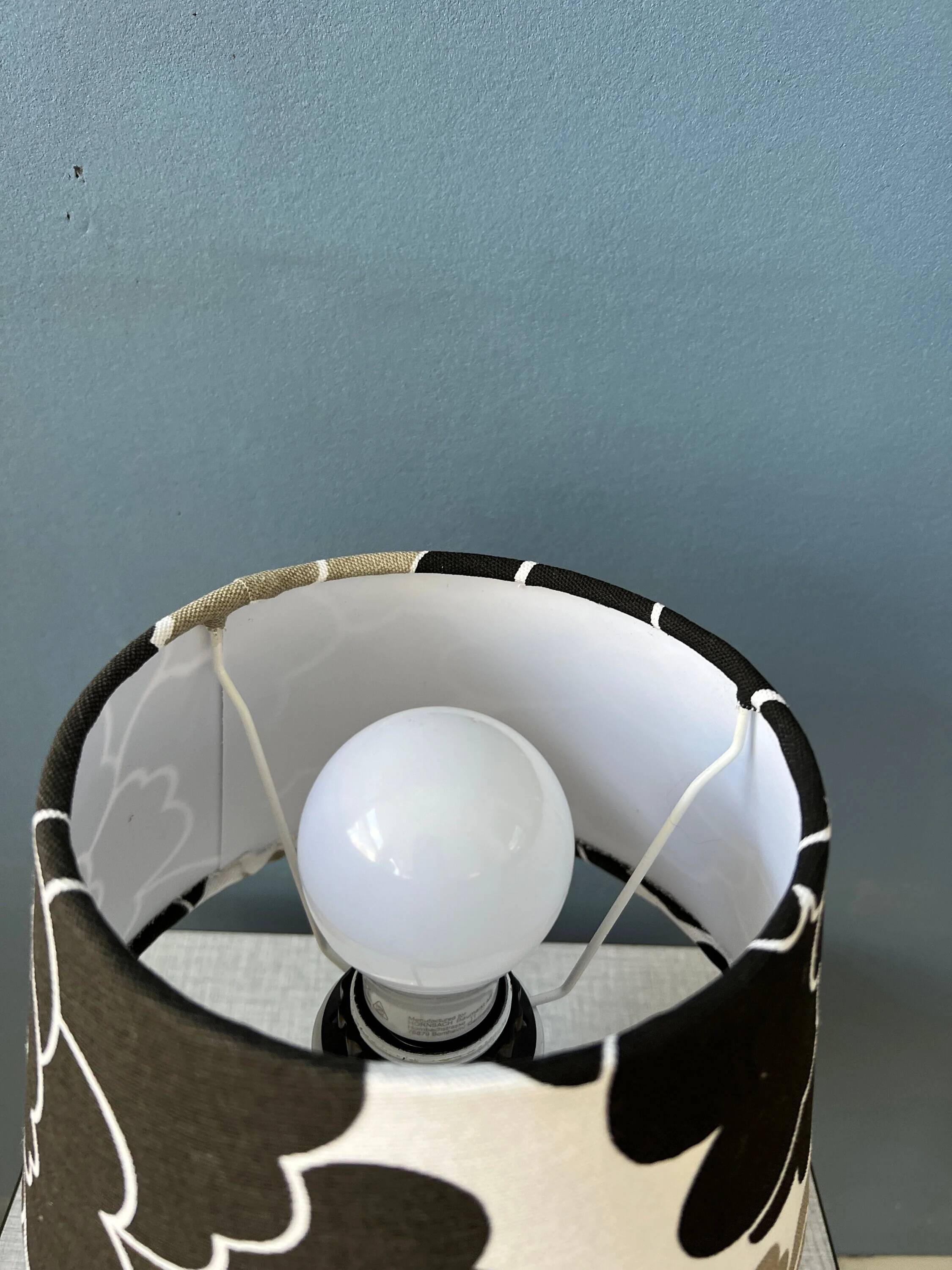 Small Space Age table lamp with a porcelain base and black and white flower shade.