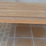 Large natural wood table with rectangular top supported by legs