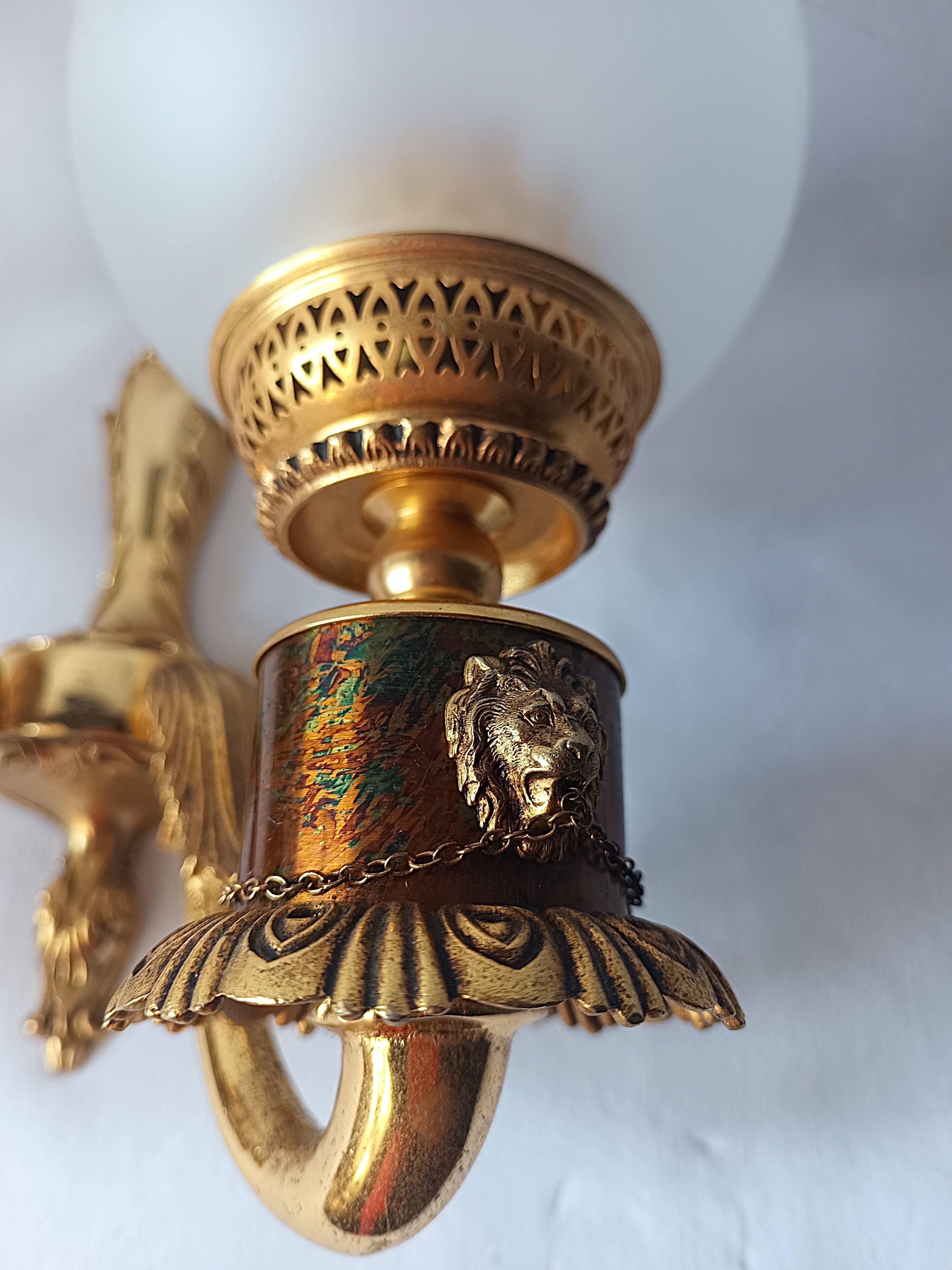Wall lamp in gilded bronze with a lion's head and engraved globe.