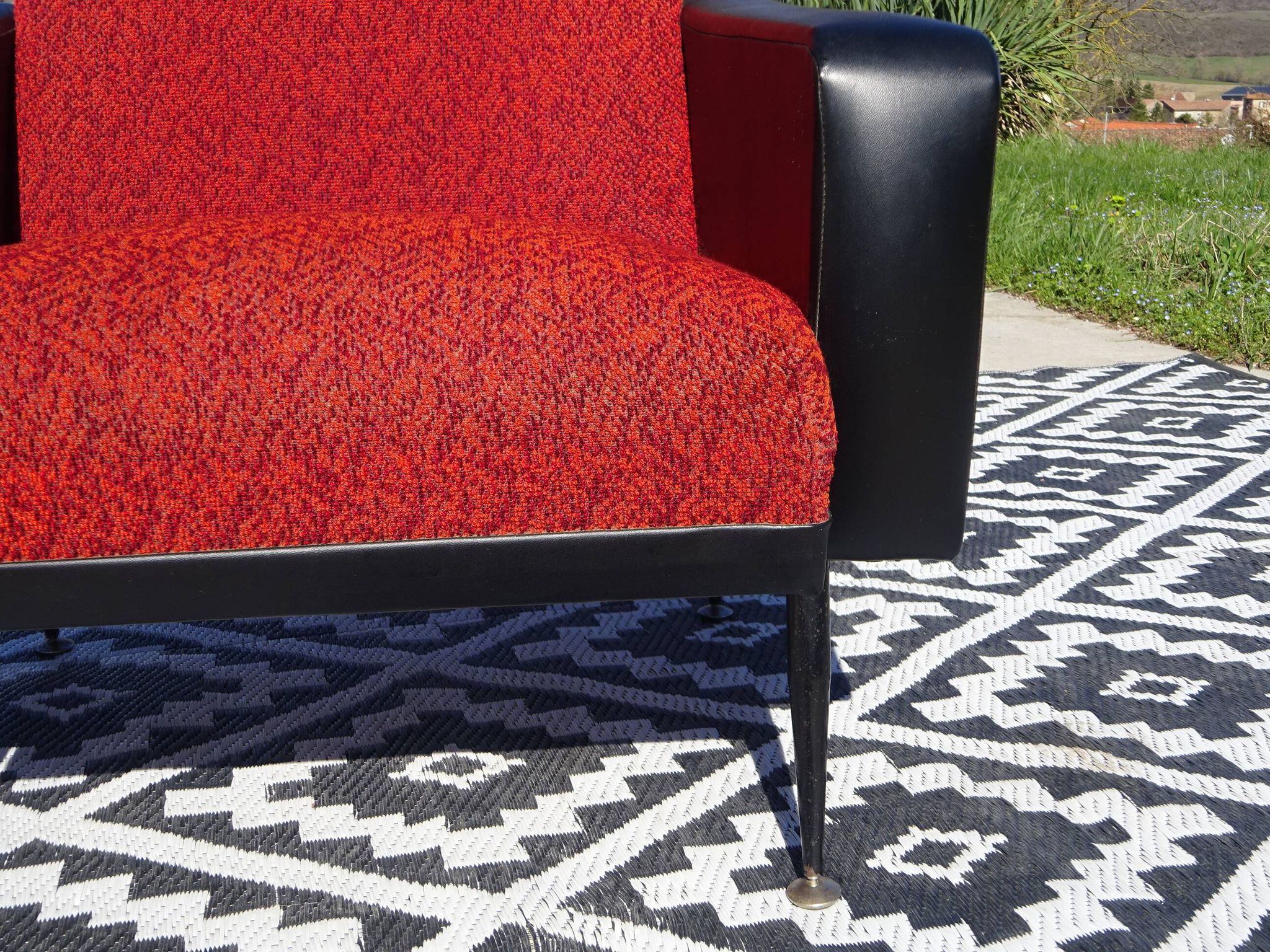 Pair of vintage armchairs in black faux leather and red fabric.