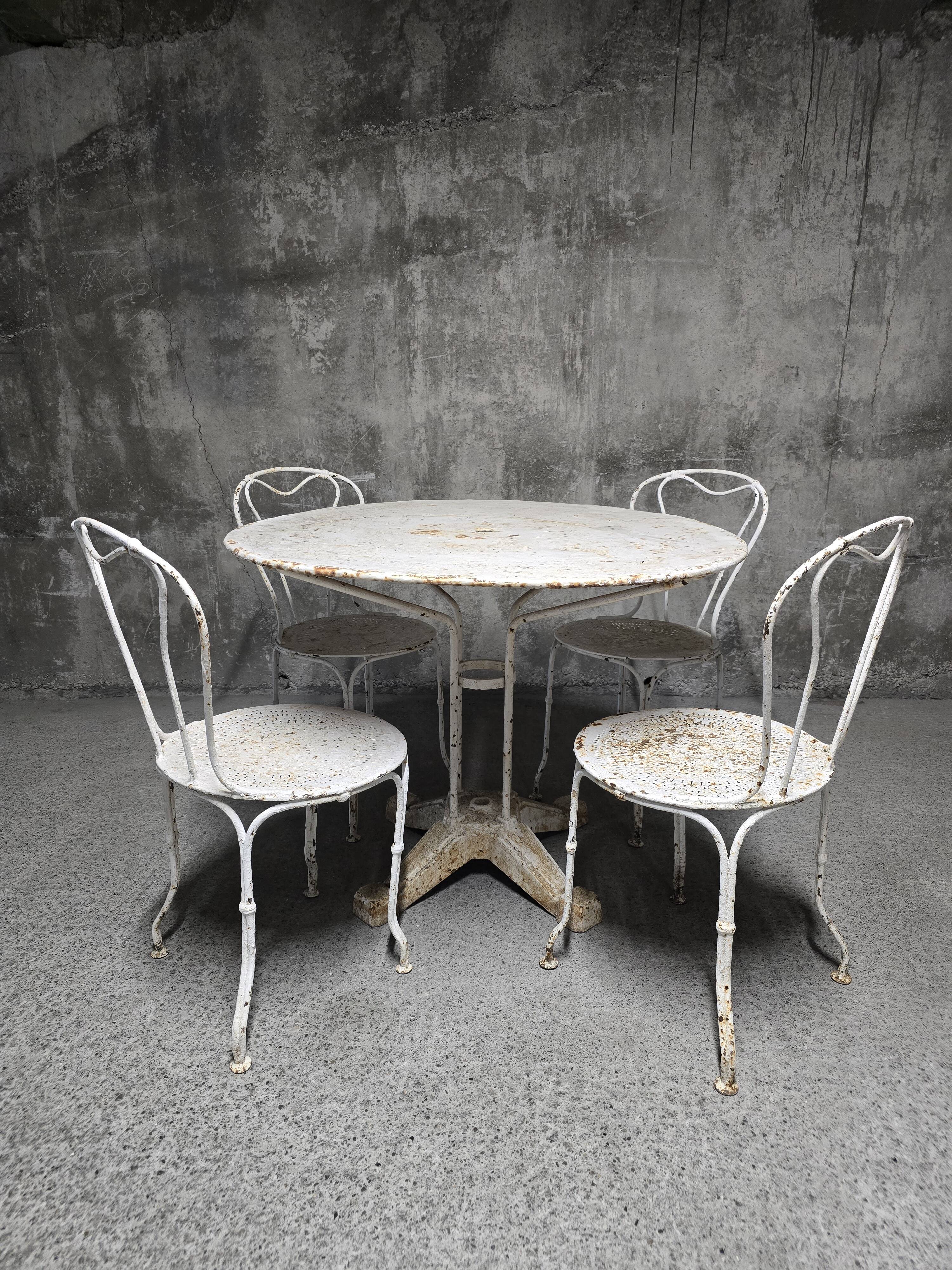Antique painted wrought iron garden furniture, round table and four chairs.