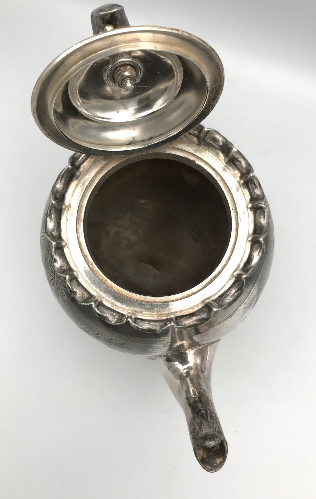 Old teapot pourer in silver metal decorated with foliage and butterflies