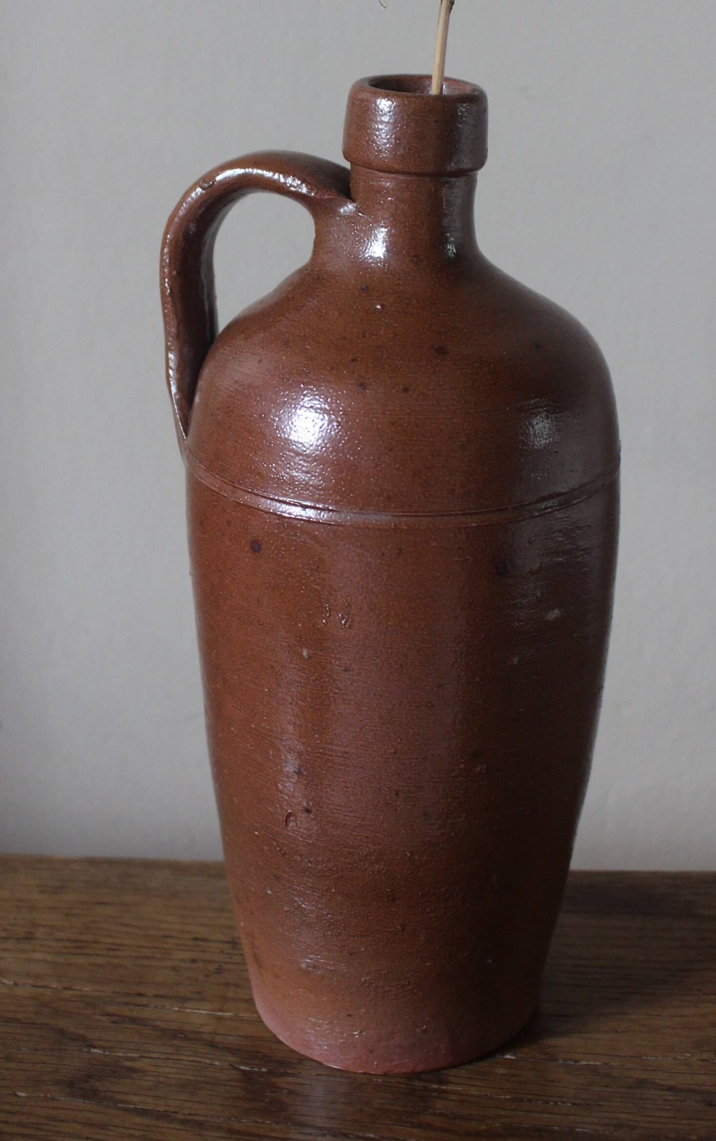 Vintage stoneware liqueur bottle with handle and spout.