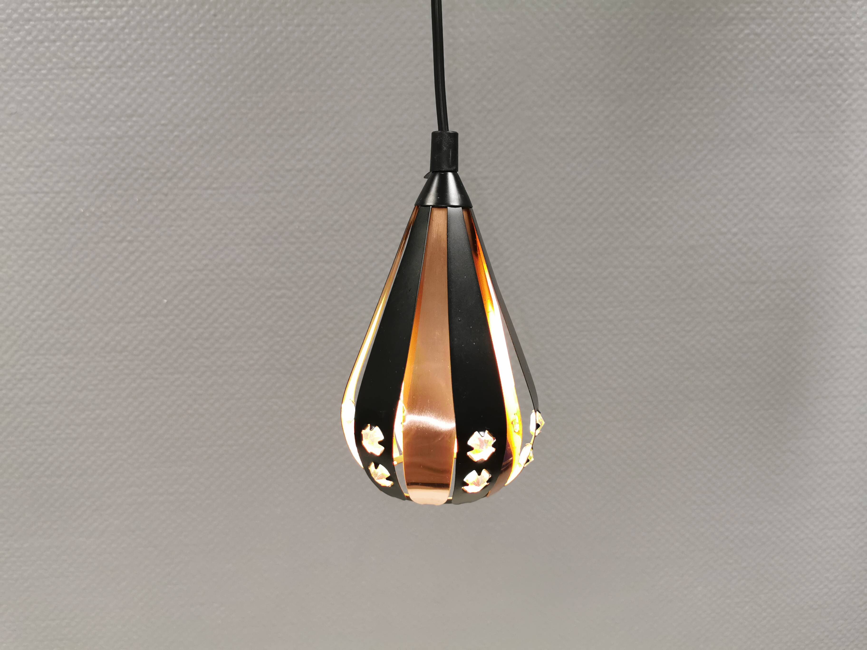 A teardrop-shaped pendant lamp made of copper, black metal, and prisms.