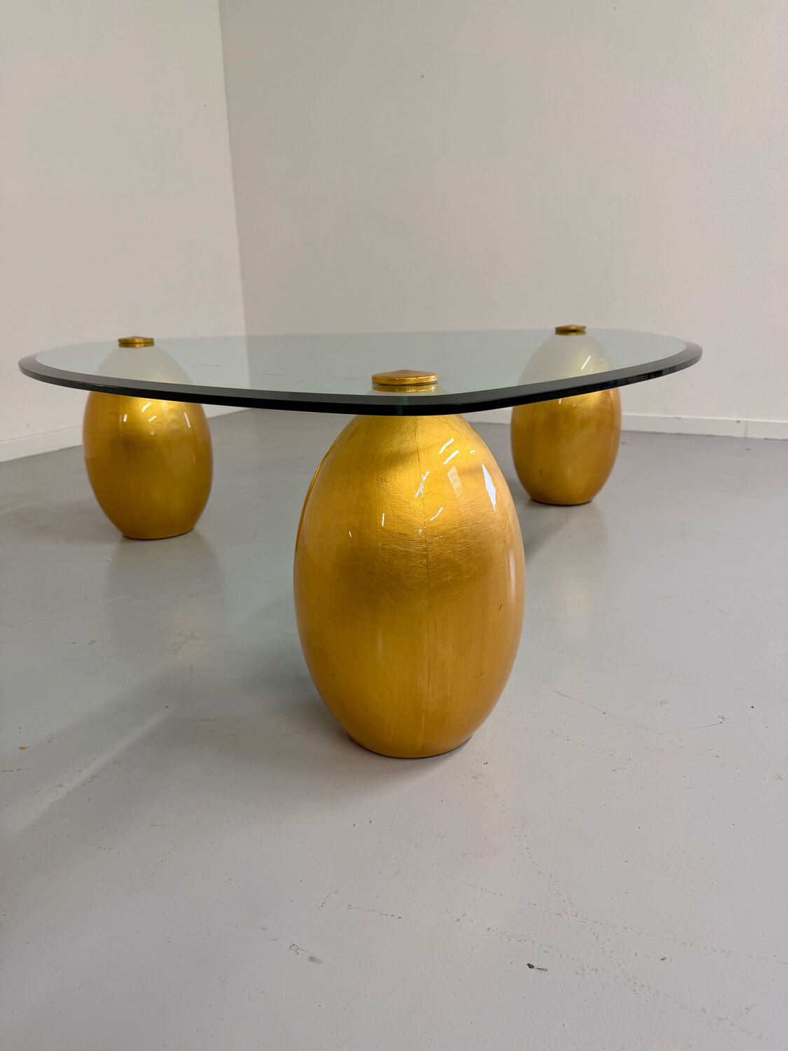 Vintage Italian design coffee table with a glass top and gold base, dating from the 1980s.